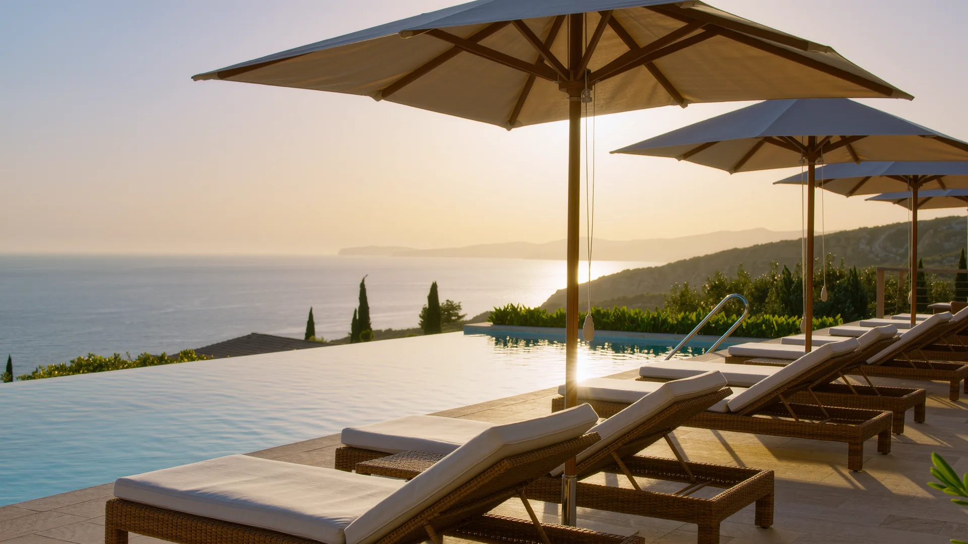 Terraza de piscina de resort con sombrillas frente al mar al atardecer
