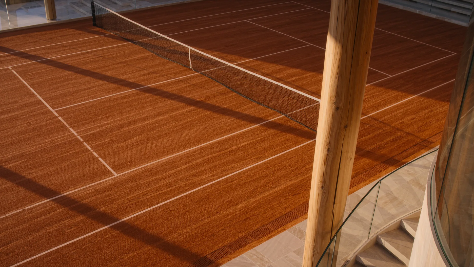 Pista de tenis de tierra batida recién barrida con sombras largas