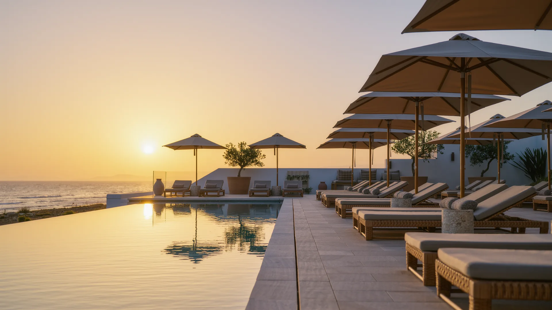 Terraza de piscina de resort con sombrillas frente al mar al atardecer