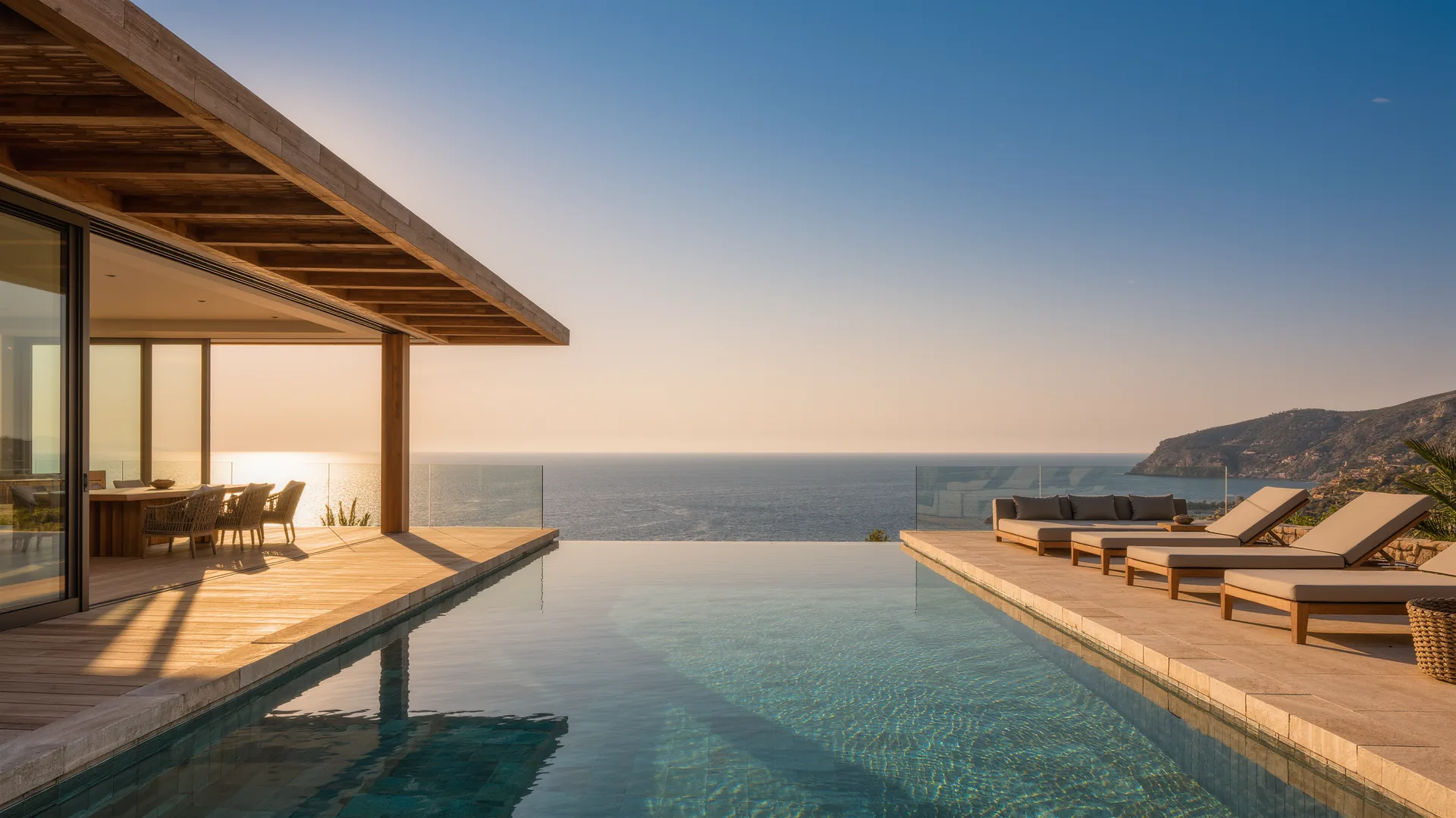 Terraza de villa moderna con piscina infinita sobre el Mediterráneo al anochecer