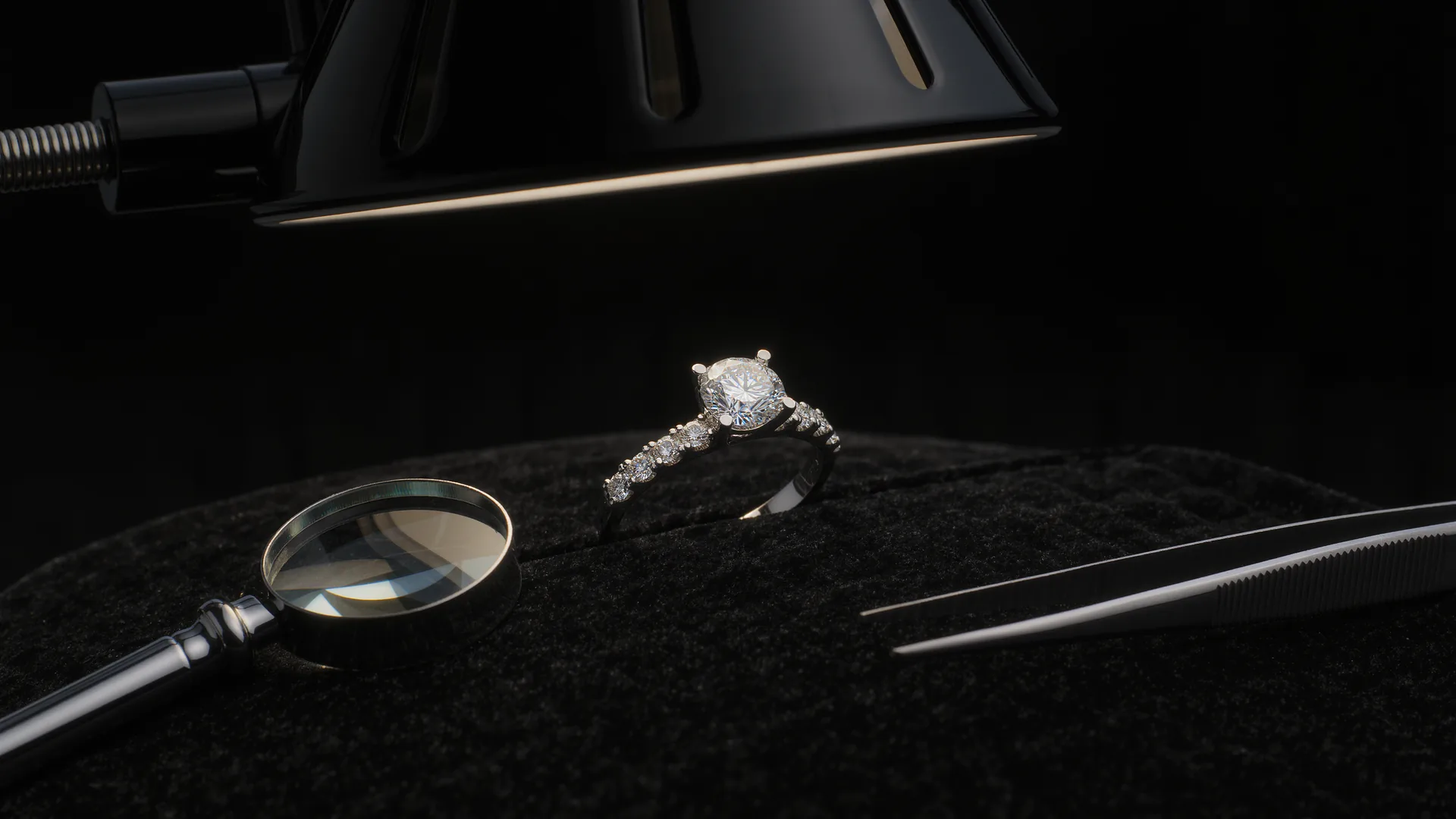 Anillo de diamantes sobre terciopelo negro bajo la lámpara del joyero, con lupa y pinzas
