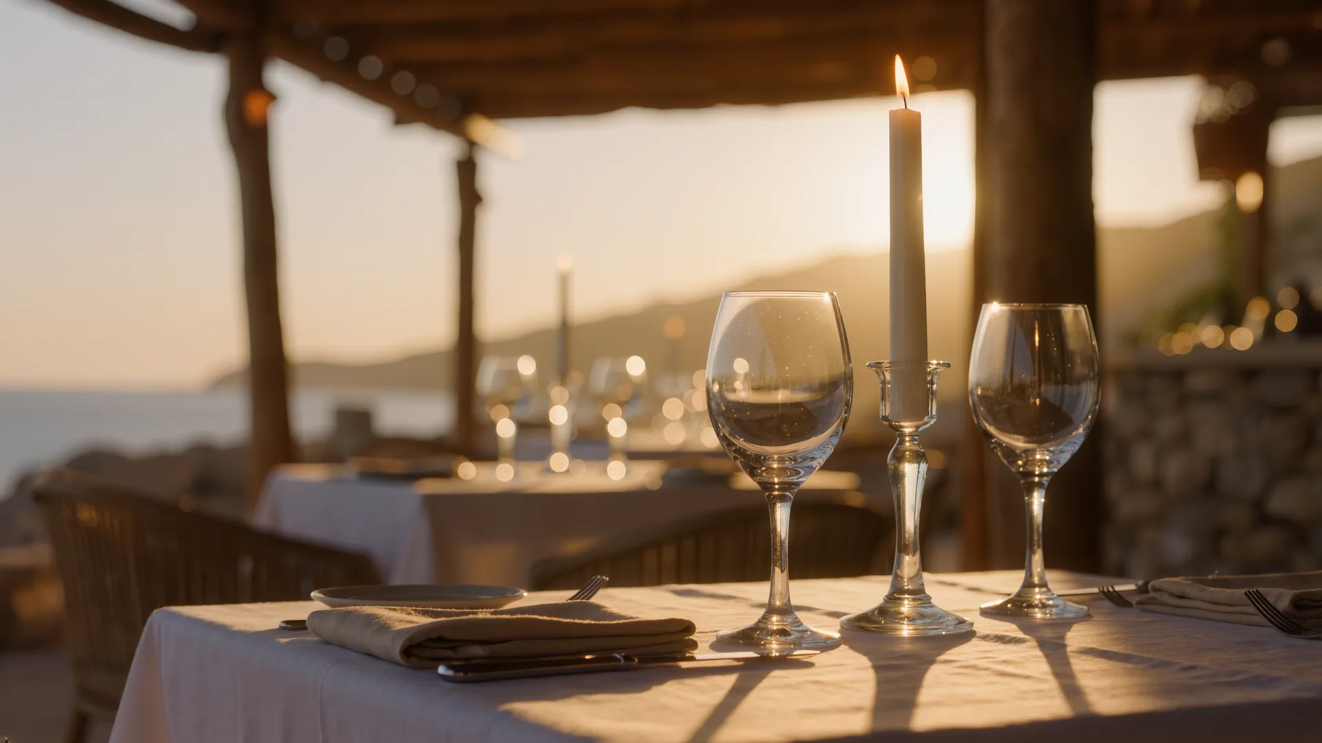 Mesa vestida con mantelería, cristalería y luz de vela, con el comedor desenfocado detrás