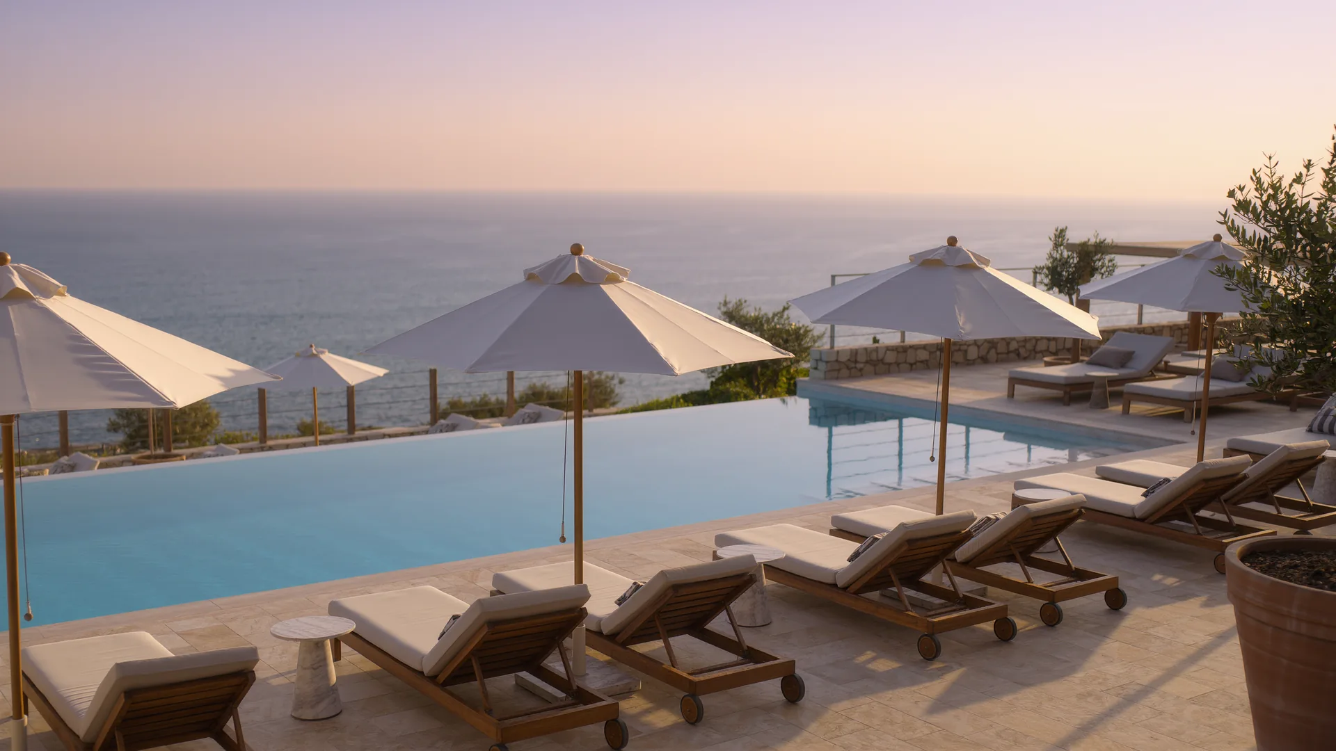 Terraza de piscina de resort con sombrillas frente al mar al atardecer
